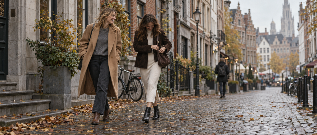 Two women walking through an old town street in autumn coats and knitwear